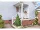 Cozy front porch area accented with red brickwork, white railings, and decorative greenery at 2312 Buckstone Ct, Fuquay Varina, NC 27526