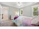 Bright bedroom features a neutral carpet, ceiling fan, a dresser, and view to outside at 2409 Basil Dr, Raleigh, NC 27612