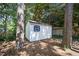 Backyard shed featuring a white exterior, blue shutters, and double doors, ideal for storage and organization at 2409 Basil Dr, Raleigh, NC 27612