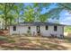 The backyard features a white-painted brick ranch home with a black roof, a small deck, and mature trees at 2609 Elmhurst Cir, Raleigh, NC 27610