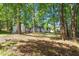 A lush, wooded backyard with mature trees offers privacy and seclusion around the white-painted ranch home at 2609 Elmhurst Cir, Raleigh, NC 27610