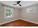 Bright bedroom featuring hardwood floors, two windows overlooking the yard, and a ceiling fan at 2609 Elmhurst Cir, Raleigh, NC 27610