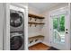 Laundry room features stackable washer/dryer, wooden shelves, and back door at 2609 Elmhurst Cir, Raleigh, NC 27610