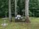 Secluded backyard seating area amidst trees, features a white wicker chair and bird bath for relaxation at 3652 E Cotton Gin Dr, Clayton, NC 27527