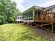 Exterior view of the home featuring a sunroom and a wooden deck surrounded by lush greenery at 3652 E Cotton Gin Dr, Clayton, NC 27527