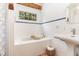 Bright bathroom showcasing tiled walls, a pedestal sink, a shower-tub combination, and natural light from the window at 3822 Chicken Bridge Rd, Pittsboro, NC 27312