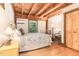 Cozy bedroom features exposed beams, wood ceiling, light hardwood floors, and a bed with decorative pillows at 3822 Chicken Bridge Rd, Pittsboro, NC 27312