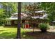 Well maintained wooden home with a red door, metal roof, and mature trees on a grassy lot at 3822 Chicken Bridge Rd, Pittsboro, NC 27312