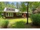 The inviting exterior has a red door, beautiful wood, a metal roof, and lush landscaping at 3822 Chicken Bridge Rd, Pittsboro, NC 27312