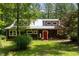 Charming wood home features a red front door, metal roof, and beautifully landscaped front yard at 3822 Chicken Bridge Rd, Pittsboro, NC 27312