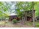 Charming exterior of a rustic cabin home with a metal roof and cozy porch and lots of surrounding greenery at 3822 Chicken Bridge Rd, Pittsboro, NC 27312