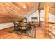 Attic living space with wood ceiling and floors with seating for four and a sofa at 3822 Chicken Bridge Rd, Pittsboro, NC 27312