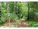 Secluded wooded walking path with sign, offering a peaceful retreat into nature at 3822 Chicken Bridge Rd, Pittsboro, NC 27312