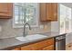 Close up of a kitchen sink featuring a stainless steel dishwasher and solid surface countertops at 3921 Robins Nest Ln, Wake Forest, NC 27587