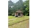 Exterior of a wooden outbuilding in a grassy area, surrounded by mature trees at 394 Flanagan Rd, Henderson, NC 27537