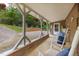 Inviting covered porch with rocking chairs, hanging plants, and a glimpse of outdoor seating on a gravel ground at 394 Flanagan Rd, Henderson, NC 27537