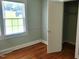 Light filled bedroom featuring hardwood floors, neutral paint, and a closet for storage at 411 W Raleigh St, Siler City, NC 27344
