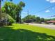 View of a well-maintained lawn with a partial view of a quaint house, set against a backdrop of trees and a sunny sky at 411 W Raleigh St, Siler City, NC 27344