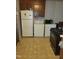 Small kitchen with white fridge, washer, dryer, dark cabinets, and dated laminate flooring at 411 W Raleigh St, Siler City, NC 27344
