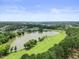 An aerial view features a lake and golf course surrounded by lush greenery and homes in the distance at 4229 Cats Paw Ct, Wake Forest, NC 27587