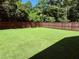 A fenced backyard with a beautiful, green lawn that has a backdrop of large, leafy trees at 451 N Lincoln St, Benson, NC 27504