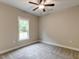 Carpeted bedroom featuring a window, neutral walls, and ceiling fan at 451 N Lincoln St, Benson, NC 27504