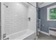 Bathroom featuring white subway tile in the shower, modern gray flooring, and a window letting in light at 503 Tarleton Ave, Burlington, NC 27215