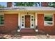 Close-up of a brick facade with a charming front door, white trim, and potted plants, creating a welcoming entrance at 503 Tarleton Ave, Burlington, NC 27215