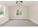 Bright bedroom with carpet flooring, a ceiling fan, and two windows offering views of the backyard at 510 Branch St, Rocky Mount, NC 27801