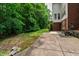 An extended concrete patio next to a lush green backyard featuring mature trees and shrubs at 5123 Richland Dr, Raleigh, NC 27612