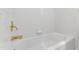A full white bathtub with brass fixtures set within white tiling at 5123 Richland Dr, Raleigh, NC 27612