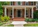 Inviting front porch with white columns, brick steps, and a black front door surrounded by sidelights and transom window at 5123 Richland Dr, Raleigh, NC 27612