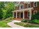 Charming brick home featuring a welcoming front porch with white columns, brick steps and walkway, and lush landscaping at 5123 Richland Dr, Raleigh, NC 27612