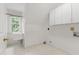Laundry room with window, utility sink, white cabinets, and white tiling at 5123 Richland Dr, Raleigh, NC 27612