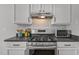 Close up shot of stainless steel gas cooktop and microwave in kitchen with mosaic tile backsplash at 5300 Roan Mountain Pl, Raleigh, NC 27613