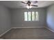 Spacious bedroom featuring neutral carpeting, a ceiling fan, and a bright window at 5893 Shady Grove Cir, Raleigh, NC 27609