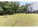 Spacious backyard with lush lawn, mature trees, a playset, and trampoline at 767 Omaha Dr, Broadway, NC 27505