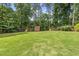 Spacious, tree-lined backyard featuring playset, trampoline, and storage sheds at 821 Van Thomas Dr, Raleigh, NC 27615