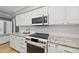 Modern kitchen with white cabinets, subway tile backsplash, stainless steel appliances, and a stylish countertop stove at 821 Van Thomas Dr, Raleigh, NC 27615