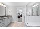 Modern bathroom featuring gray vanity, tile floors, glass-enclosed shower, and an open doorway to the bedroom at 8341 Running Fern Way, Willow Springs, NC 27592
