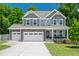 Charming two-story home showcasing a stone facade, covered porch, attached two-car garage and manicured lawn at 8341 Running Fern Way, Willow Springs, NC 27592