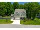 Two-story home with manicured lawn, three-car garage, and stone accents for enhanced curb appeal at 8341 Running Fern Way, Willow Springs, NC 27592