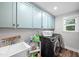 Laundry room with pale blue upper cabinets, modern washer and dryer, and a utility sink at 8341 Running Fern Way, Willow Springs, NC 27592