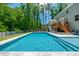 Relax in style by the pool, offering a spacious patio, outdoor seating, and a beautifully landscaped backyard with mature trees at 8341 Running Fern Way, Willow Springs, NC 27592