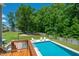 Backyard oasis offers a luxurious pool, sun loungers on the patio, and a spacious grass area for outdoor activities at 8341 Running Fern Way, Willow Springs, NC 27592