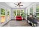 Bright sunroom featuring a cozy red couch, natural light and access to a wooden deck at 8341 Running Fern Way, Willow Springs, NC 27592