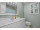 Bathroom featuring a white vanity, framed mirror, and a window with decorative shutters at 8412 Old Deer Trl, Raleigh, NC 27615