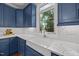 Charming kitchen featuring custom blue cabinets, a farmhouse sink, and a window overlooking the wooded backyard at 8412 Old Deer Trl, Raleigh, NC 27615