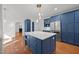 Open concept kitchen with blue cabinets, a marble-topped island, and stainless steel appliances, with views to the living area at 8412 Old Deer Trl, Raleigh, NC 27615