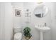 Clean and bright bathroom with a pedestal sink, toilet, framed artwork, and decorative plants at 9021 Winged Thistle Ct, Raleigh, NC 27617